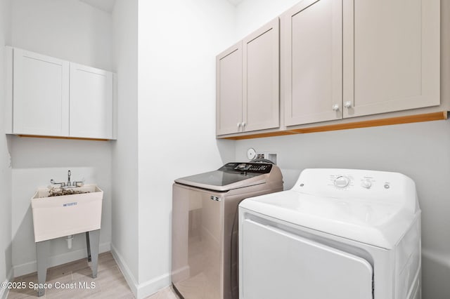 laundry area with cabinets, washer and clothes dryer, and light hardwood / wood-style flooring