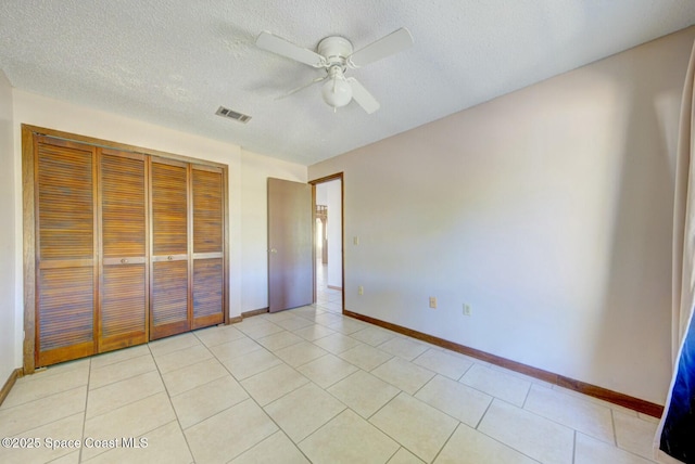 unfurnished bedroom with a textured ceiling, ceiling fan, and a closet