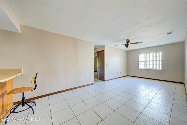 tiled spare room with a textured ceiling and ceiling fan