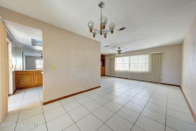 spare room featuring ceiling fan with notable chandelier and light tile patterned floors