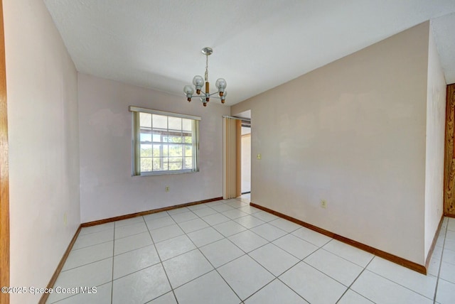 tiled empty room featuring a chandelier