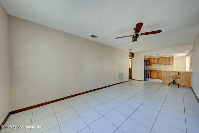 unfurnished living room featuring ceiling fan, a textured ceiling, and light tile patterned floors