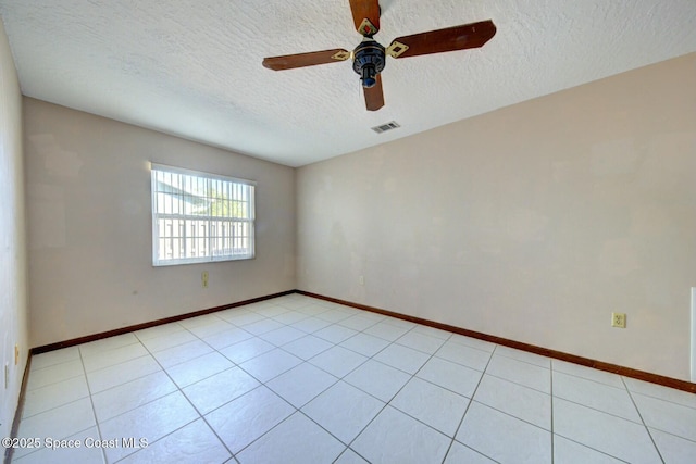 spare room featuring ceiling fan, light tile patterned flooring, and a textured ceiling