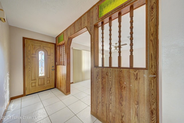 foyer featuring wooden walls and light tile patterned flooring