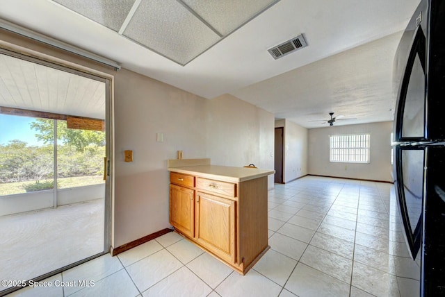 kitchen with kitchen peninsula, ceiling fan, light tile patterned floors, and black refrigerator