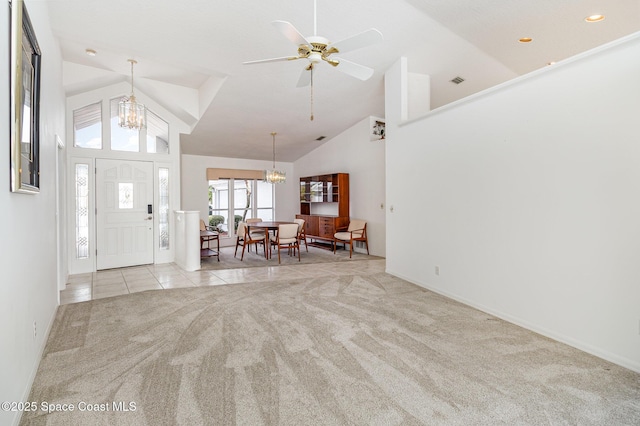 carpeted entryway with high vaulted ceiling and ceiling fan with notable chandelier