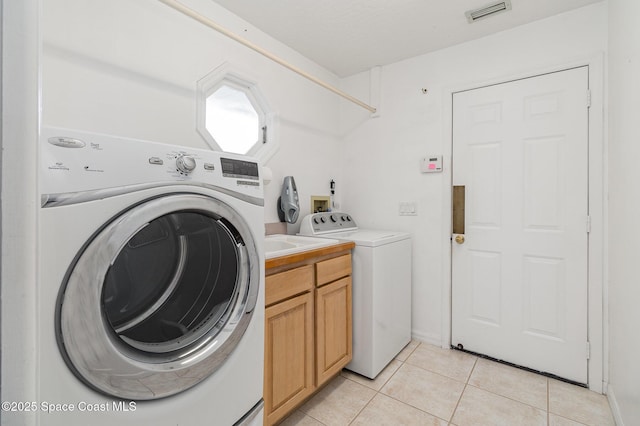 washroom with cabinets, washing machine and dryer, and light tile patterned flooring