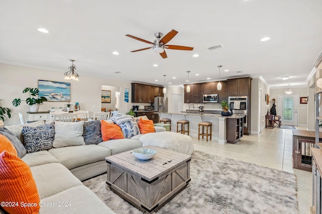 tiled living room with ornamental molding, ceiling fan with notable chandelier, and sink