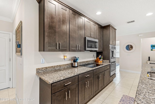 kitchen featuring light tile patterned flooring, stainless steel appliances, ornamental molding, dark brown cabinets, and light stone counters