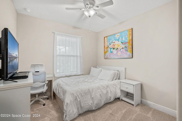 bedroom with ceiling fan, light colored carpet, and a textured ceiling