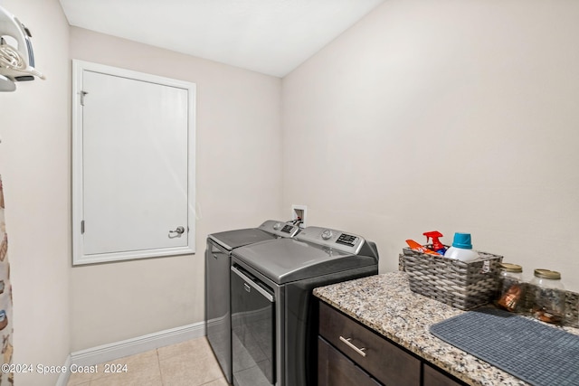 washroom with sink, washing machine and dryer, light tile patterned flooring, and cabinets