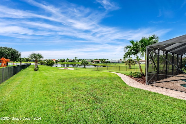 view of yard with glass enclosure and a water view