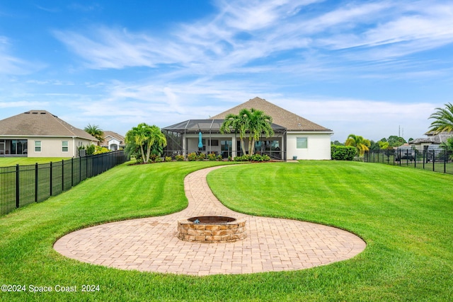 back of house with a lanai, an outdoor fire pit, and a lawn