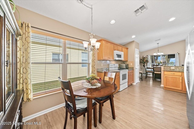 dining space featuring light hardwood / wood-style floors, vaulted ceiling, and a notable chandelier