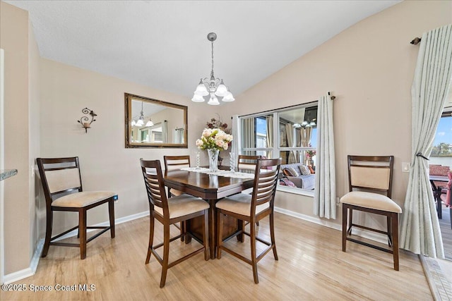 dining area with lofted ceiling, a notable chandelier, and light wood-type flooring