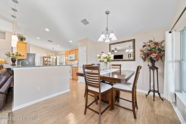 dining area with lofted ceiling, light wood-type flooring, and a chandelier