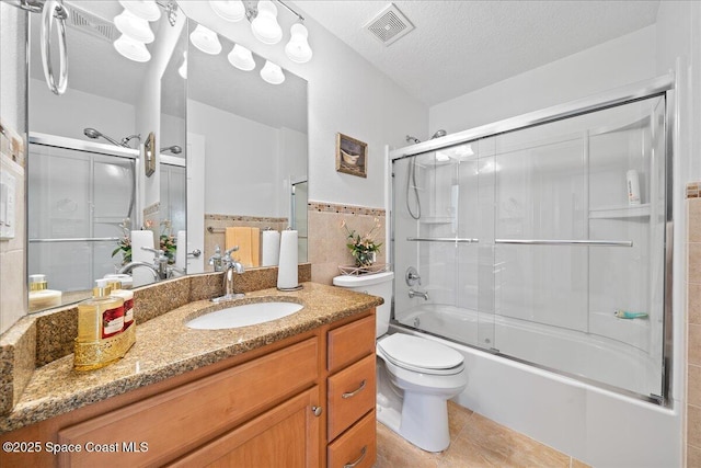 full bathroom with shower / bath combination with glass door, vanity, a textured ceiling, tile patterned floors, and toilet