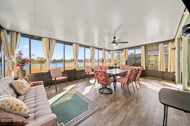 sunroom / solarium featuring ceiling fan, a healthy amount of sunlight, and a water view