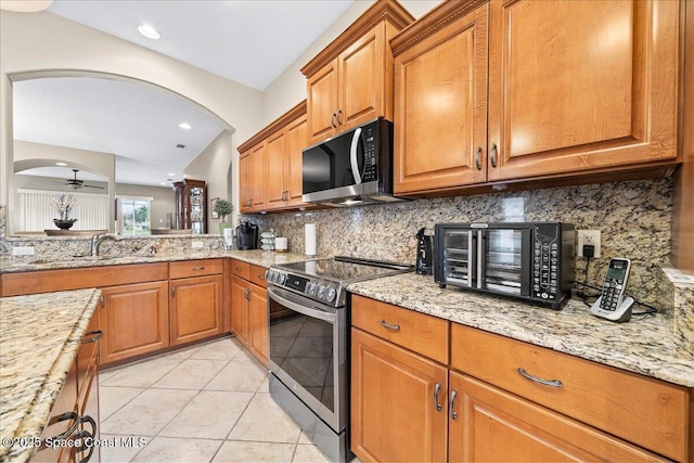 kitchen with ceiling fan, sink, backsplash, and stainless steel range with electric stovetop