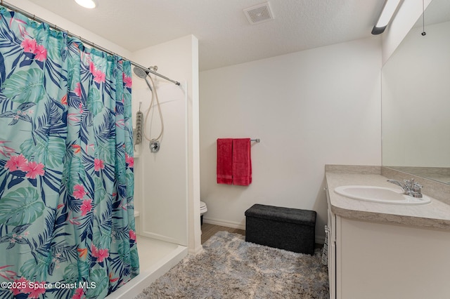 bathroom featuring a textured ceiling, toilet, a shower with curtain, and vanity