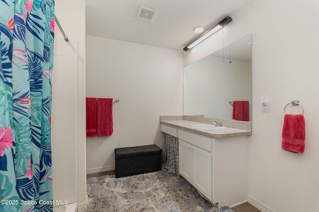 bathroom with curtained shower, a textured ceiling, and vanity