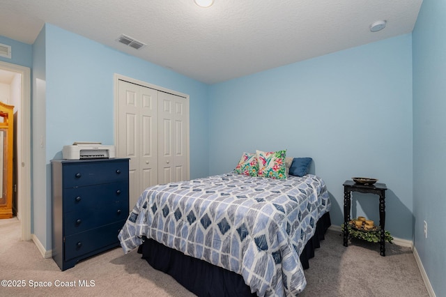 carpeted bedroom featuring a textured ceiling and a closet