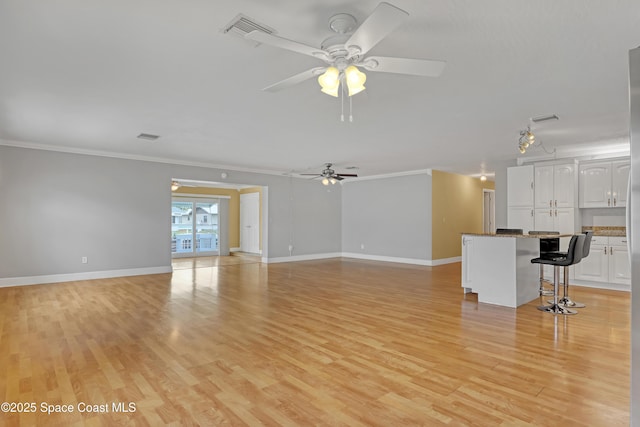 unfurnished living room featuring ceiling fan, ornamental molding, and light hardwood / wood-style flooring