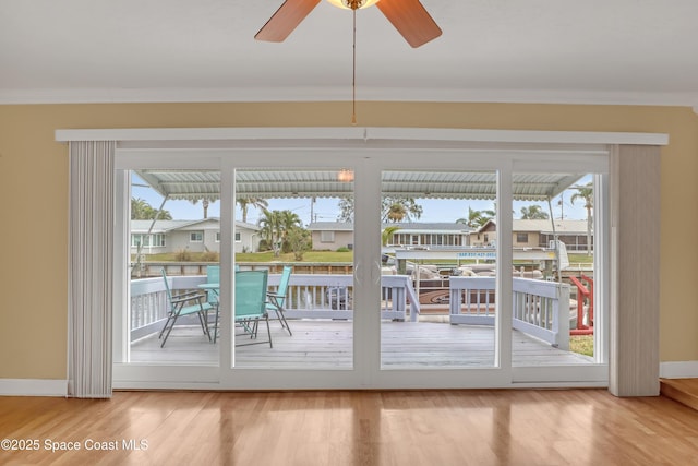 doorway with ceiling fan, hardwood / wood-style floors, crown molding, and plenty of natural light