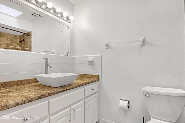 bathroom with backsplash, toilet, vanity, and walk in shower