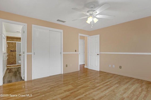 unfurnished bedroom with ceiling fan, a closet, light hardwood / wood-style floors, and ensuite bath