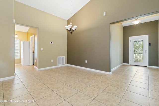 spare room featuring light tile patterned floors, vaulted ceiling, a notable chandelier, and plenty of natural light