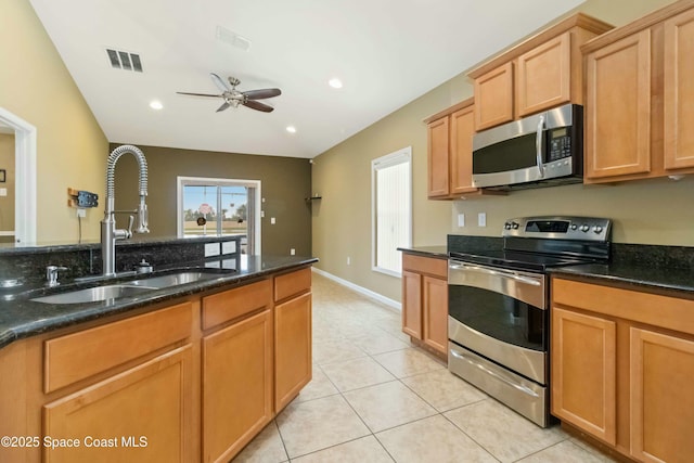 kitchen with stainless steel appliances, dark stone counters, and sink