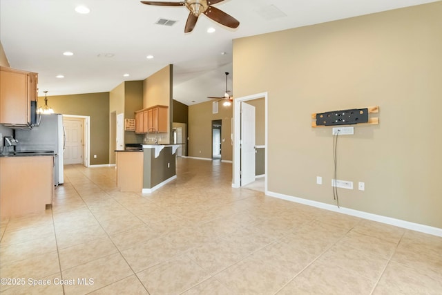 kitchen with light tile patterned flooring, ceiling fan with notable chandelier, kitchen peninsula, and a kitchen bar