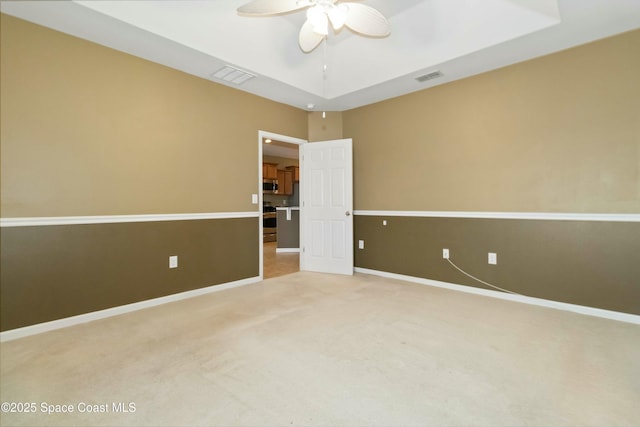 spare room with ceiling fan, carpet, and a tray ceiling