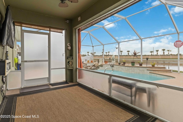 view of swimming pool featuring ceiling fan, glass enclosure, a water view, and a patio