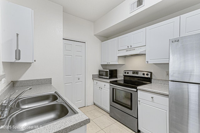 kitchen with light tile patterned floors, sink, stainless steel appliances, and white cabinetry