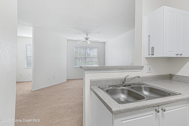 kitchen featuring white cabinetry, kitchen peninsula, ceiling fan, light colored carpet, and sink