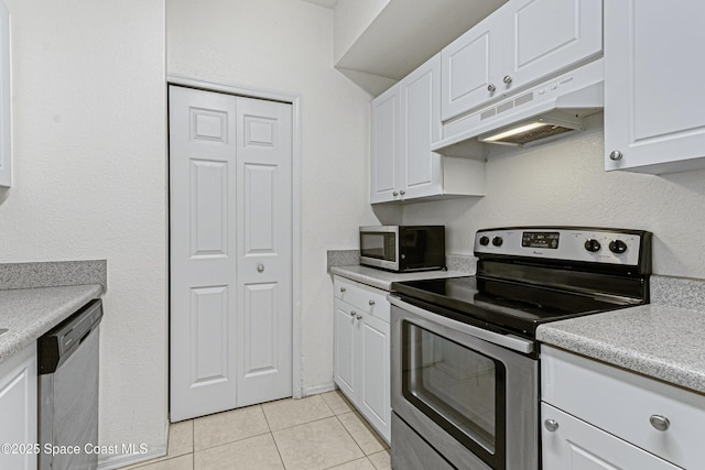 kitchen with light tile patterned floors, appliances with stainless steel finishes, and white cabinetry