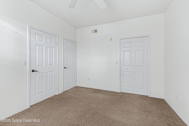 unfurnished bedroom featuring ceiling fan, carpet, and two closets