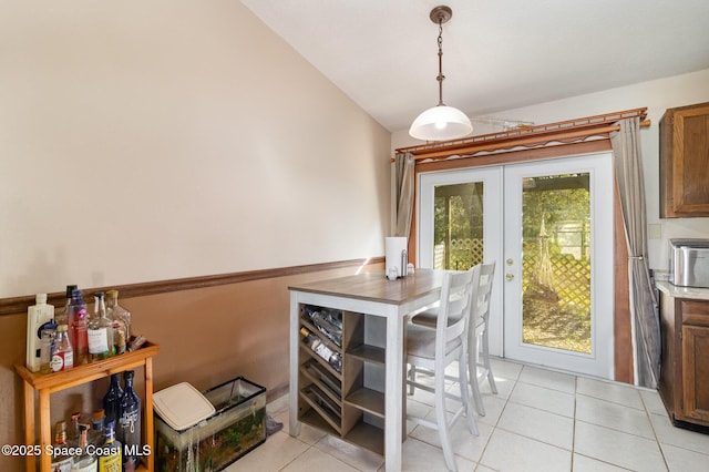 dining room featuring light tile patterned floors, french doors, and vaulted ceiling