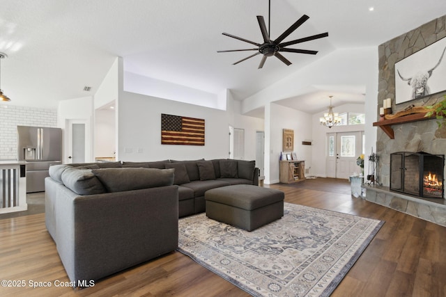 living room featuring an inviting chandelier, a stone fireplace, high vaulted ceiling, and hardwood / wood-style flooring