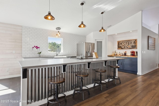 kitchen featuring dark hardwood / wood-style floors, decorative light fixtures, a kitchen breakfast bar, stainless steel refrigerator with ice dispenser, and blue cabinetry