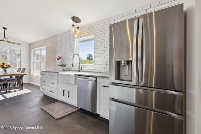 kitchen featuring pendant lighting, sink, appliances with stainless steel finishes, white cabinetry, and tasteful backsplash