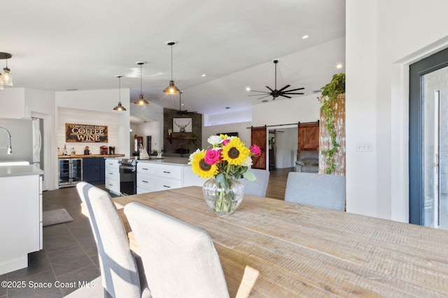 tiled dining space featuring vaulted ceiling, a barn door, and indoor bar