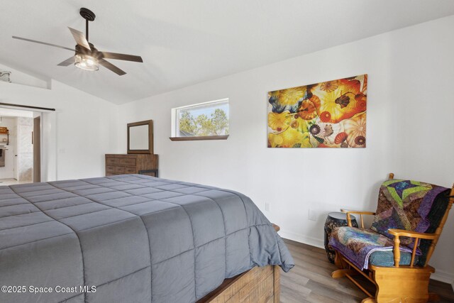 bedroom with ceiling fan, vaulted ceiling, and wood-type flooring