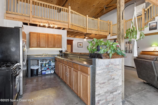 kitchen featuring ceiling fan, black range with gas stovetop, kitchen peninsula, and a high ceiling