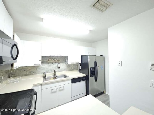 kitchen with sink, white cabinetry, stainless steel refrigerator with ice dispenser, white dishwasher, and a textured ceiling