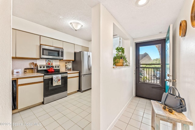 kitchen featuring stainless steel appliances, light countertops, light tile patterned flooring, a textured ceiling, and baseboards