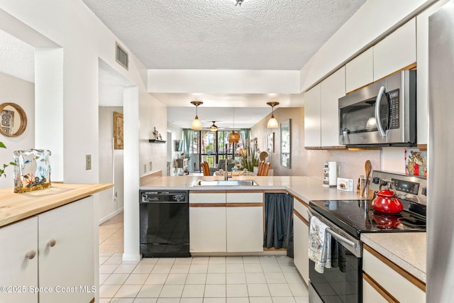 kitchen featuring white cabinets, appliances with stainless steel finishes, a peninsula, hanging light fixtures, and light countertops