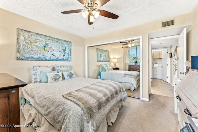 bedroom featuring a textured ceiling, light carpet, visible vents, a closet, and washer / dryer